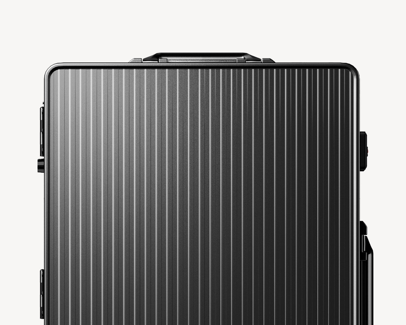 Image of a sleek, metallic-black, ribbed hard-shell aluminium luggage seen from the front, with visible side handles and a retractable top handle, against a light background.