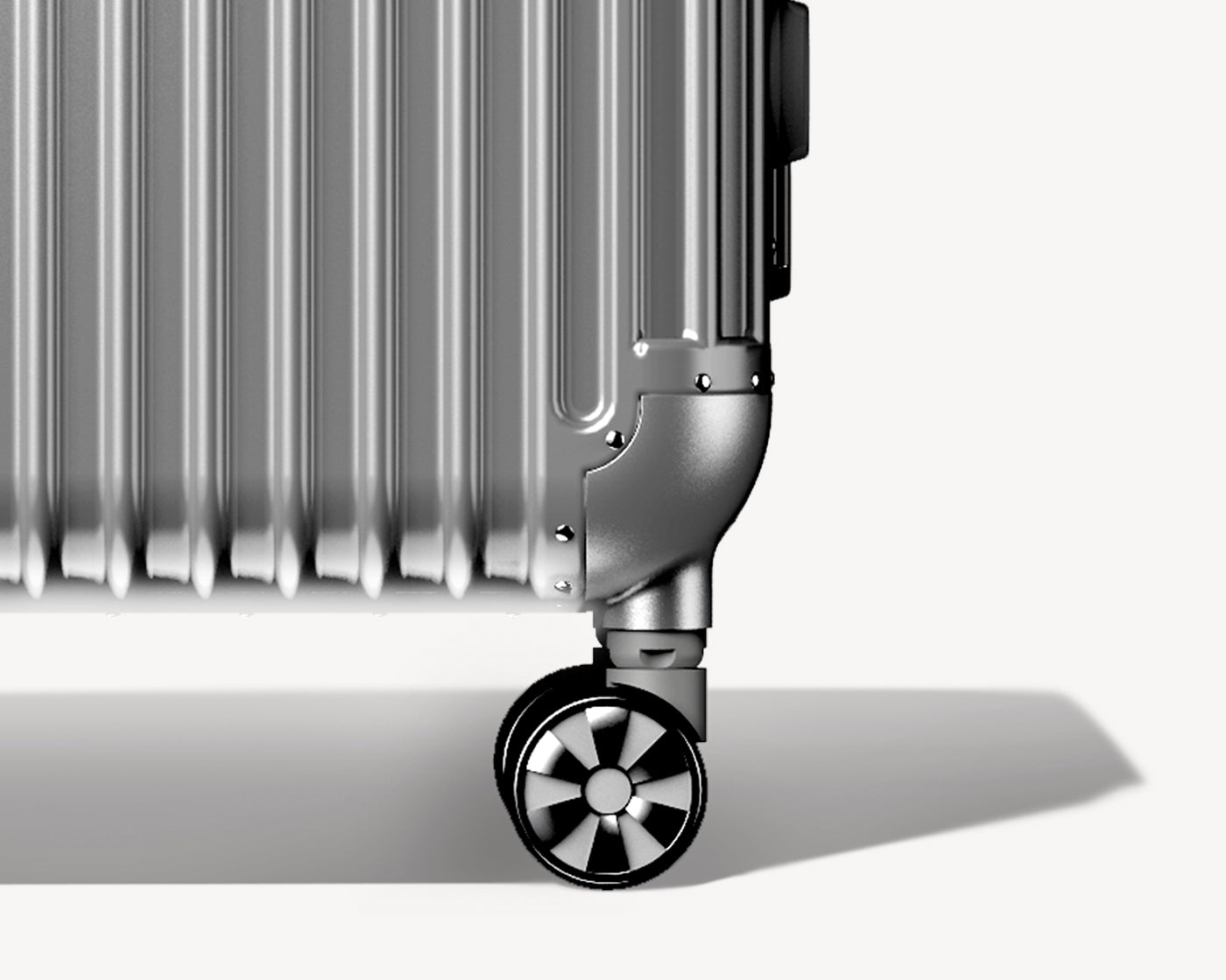 Detailed view of the bottom corner of a silver metallic luggage showing the wheel and lower part of the retractable handle.